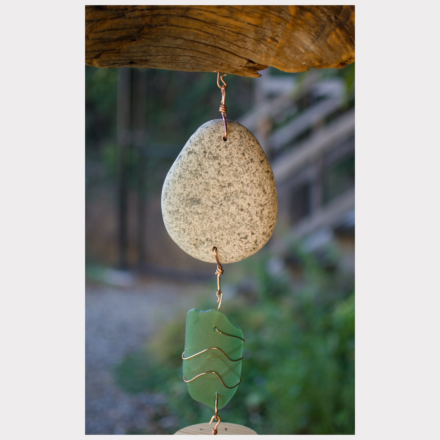 Decorative hanging stone with green glass piece against a natural background
