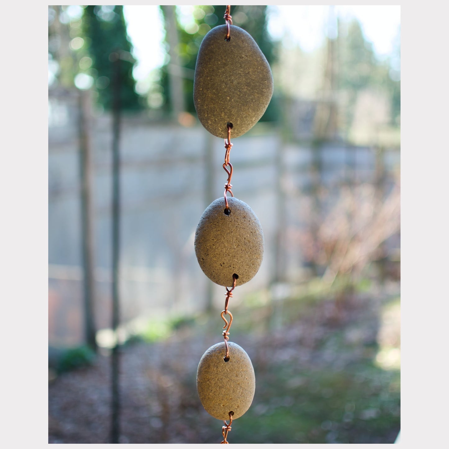 zoom detail of beach stones for a large copper wind chime