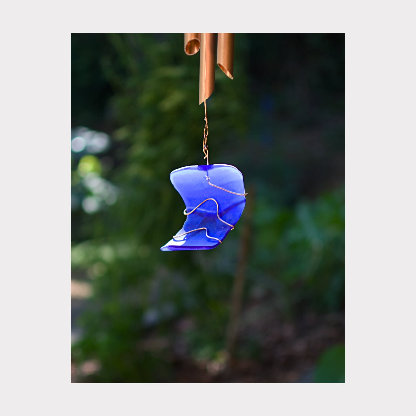Detail, cobalt blue artist-made beach glass windsail for a large copper wind chime.
