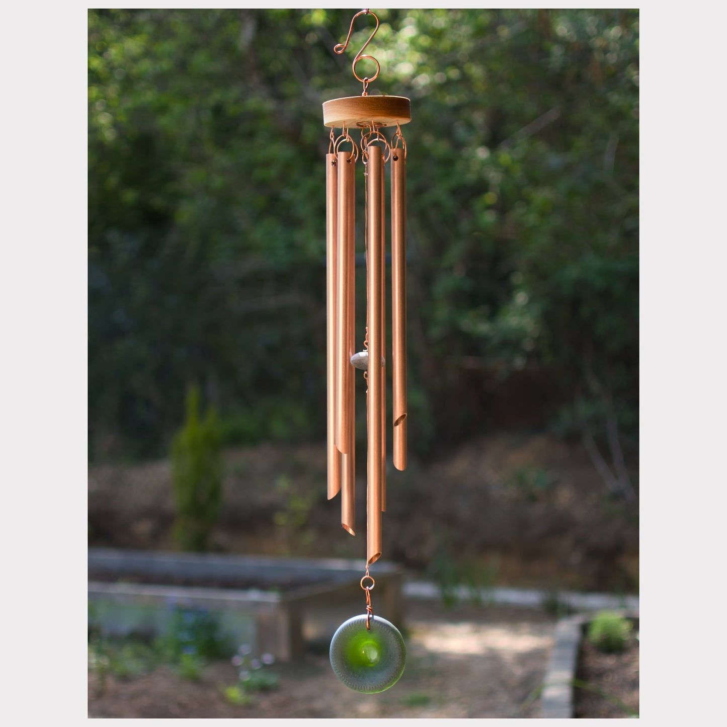 Handcrafted copper wind chime with a green glass windsail and seven chimes.