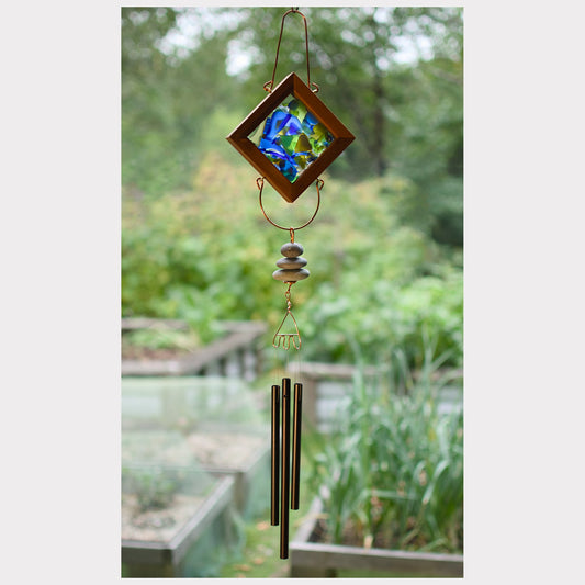 Decorative wind chime with stained glass panel in a garden setting