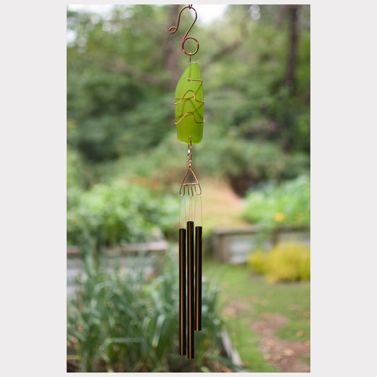 Green wind chime with blurred garden background