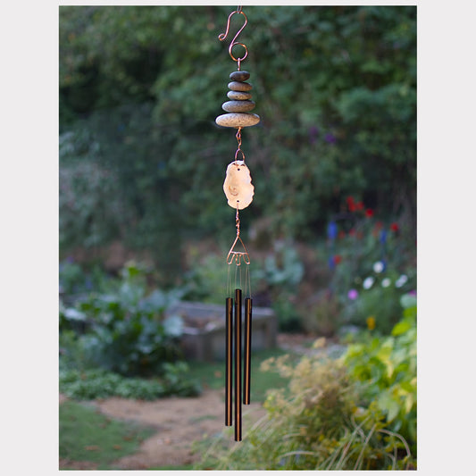 Decorative wind chime with stones and metal tubes in a garden setting