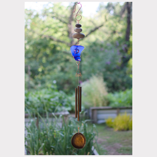 Decorative wind chime with pebble and blue glass design against a garden background