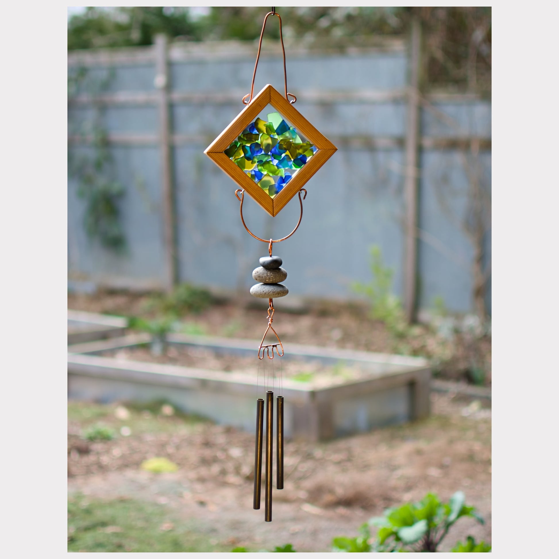 Sea glass kaleidoscope wind chime with natural beach stones and brass chimes.