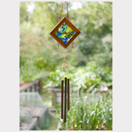 Decorative wind chime with colorful glass panel and aluminum tubes in a garden setting