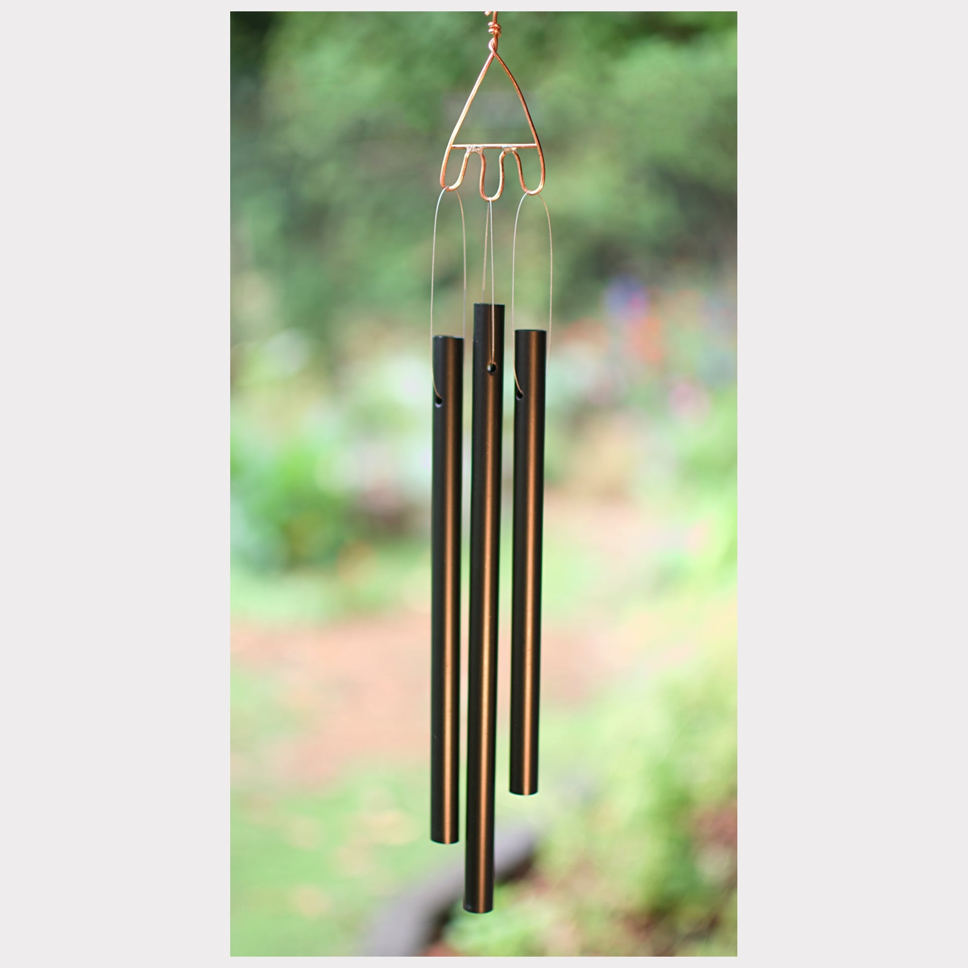 Decorative wind chime with black tubes against a blurred green background